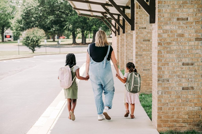 A mother with two girls picking them up from daycare.