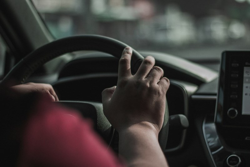A parent waits in their car to pick up their kids from school.