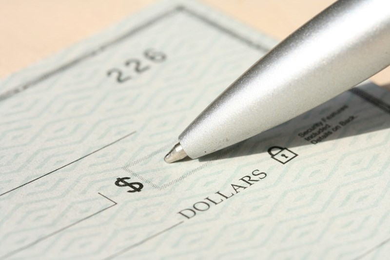 Close-up of a check and pen resting on a signature line, symbolizing an important financial decision or unexpected monetary opportunity.