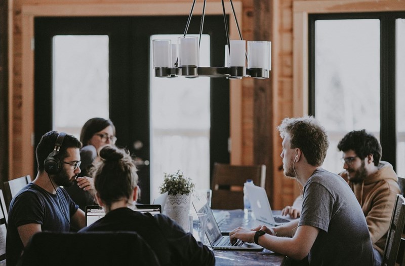 Co-workers working together and discussing diverse topics by sitting around a table.