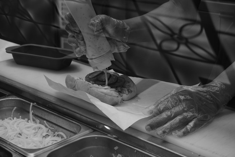 A person prepping a hamburger at a food chain.
