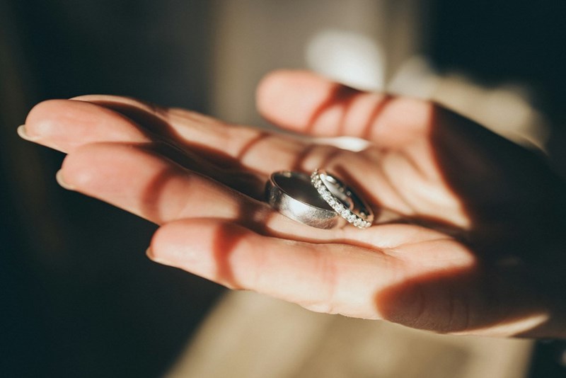 A representation of a wedding ring removed from a woman’s hand, symbolizing a separation and a conflict over a married name.