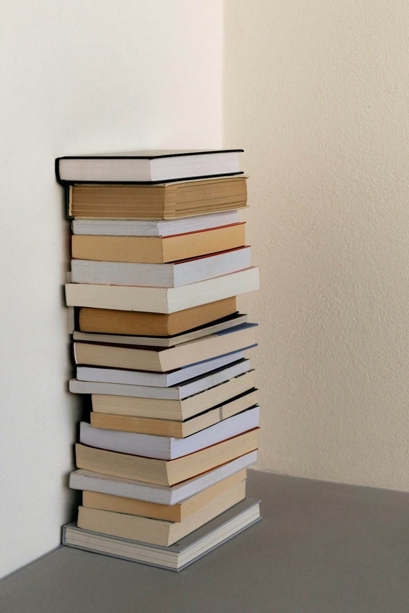 A pile of books on a desk representing an academic’s research work and professional reputation.