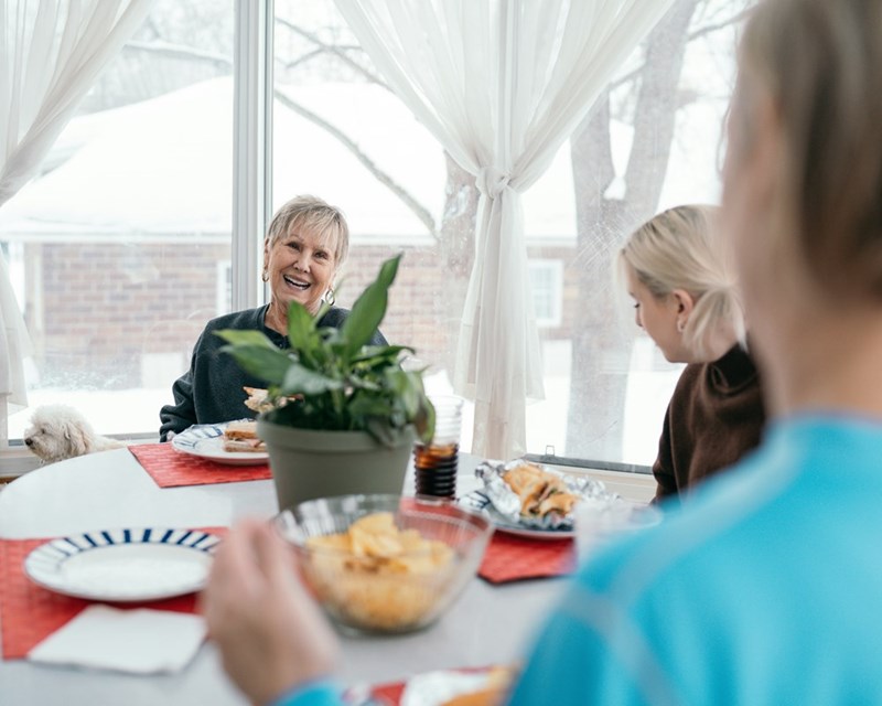 A couple and an wold woman eating breakfast in a round kitchen table.