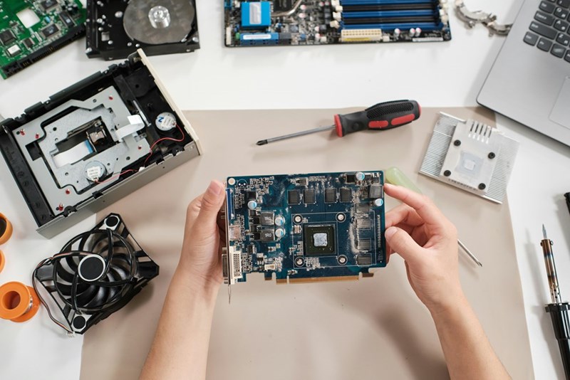 IT employee handles computer hardware and company equipment as part of a routine technology support task.