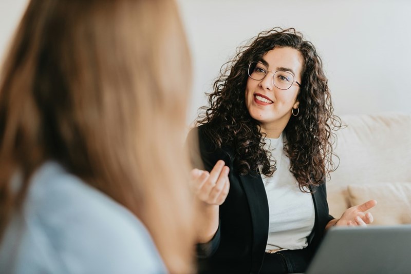 A young woman has a challenging conversation with her boss as seen from behind.