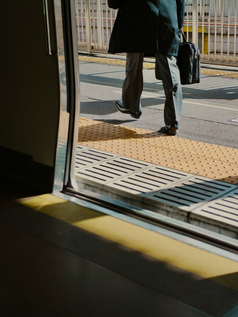 A former commuter steps off public transit, reflecting the routine office travel that some remote workers no longer need to make.