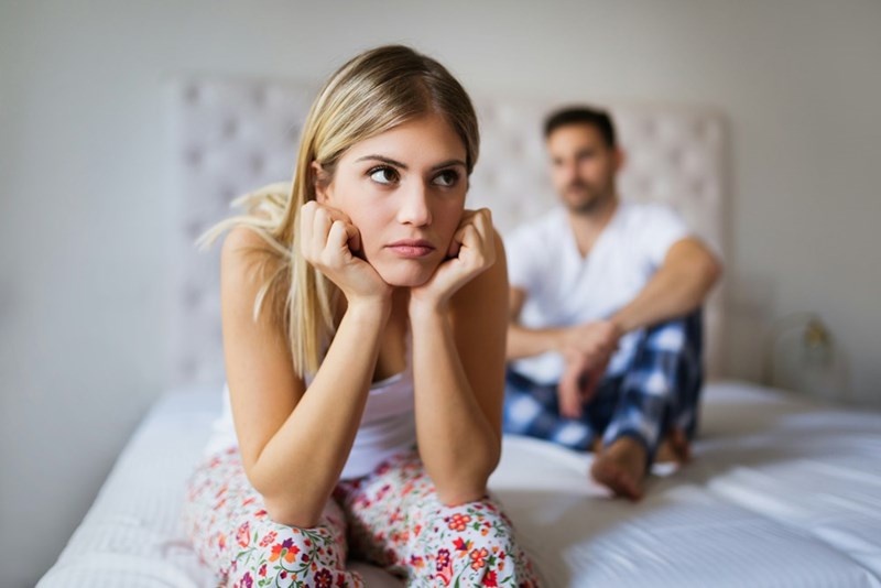 A couple sits in uncomfortable silence after an argument, reflecting a conflict that extends beyond the original disagreement.