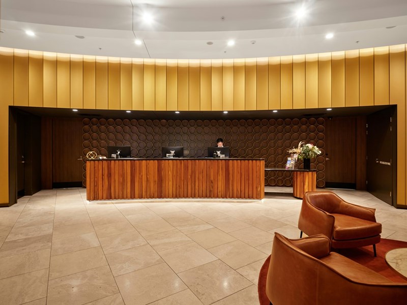 A modern hotel lobby with a front desk, showing the setting of a late-night check-in dispute over two booked rooms.