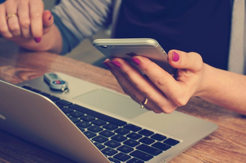 A person checking their phone and their computer at the same time.
