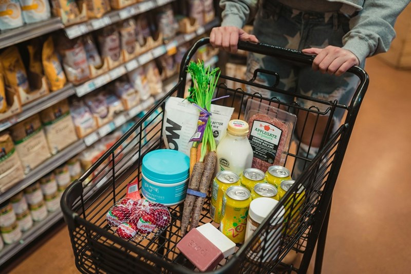 a person pushing shopping cart full of food