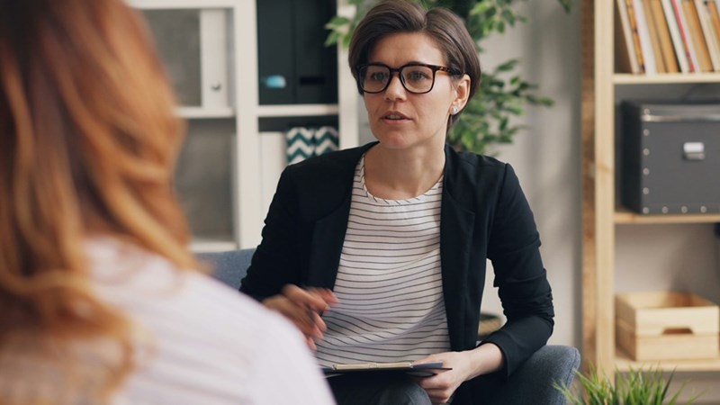 woman sitting on a couch talking to another