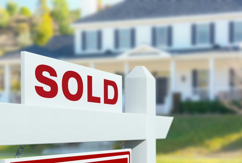 Sold house sign in front of new house.