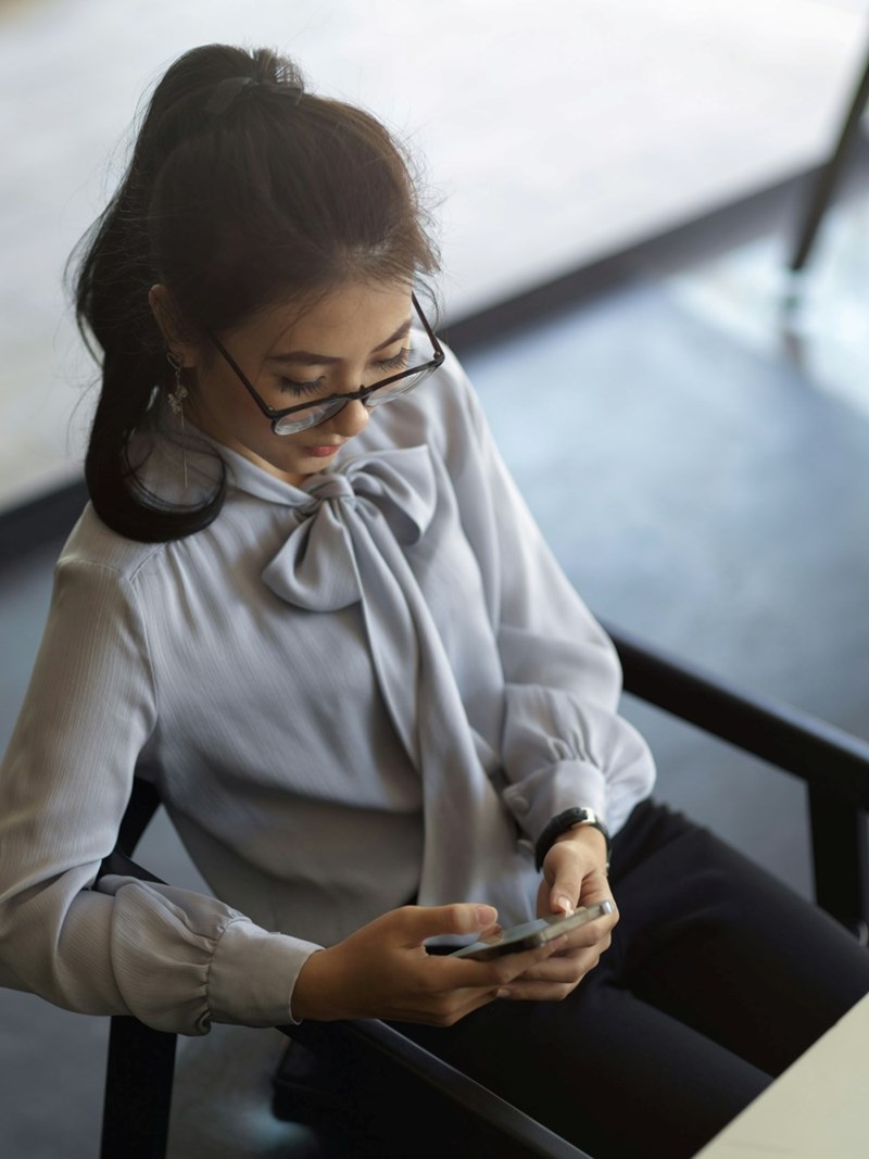 A female employee looks at her smartphone while sitting down