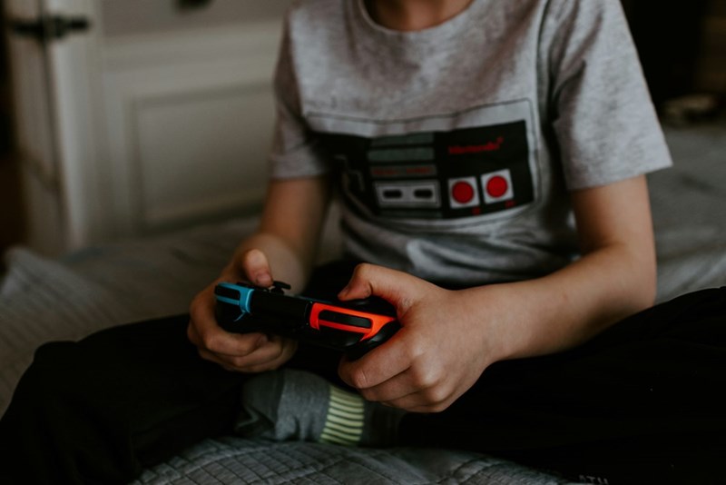 A teenage boy plays video games in his room instead of doing his French homework.