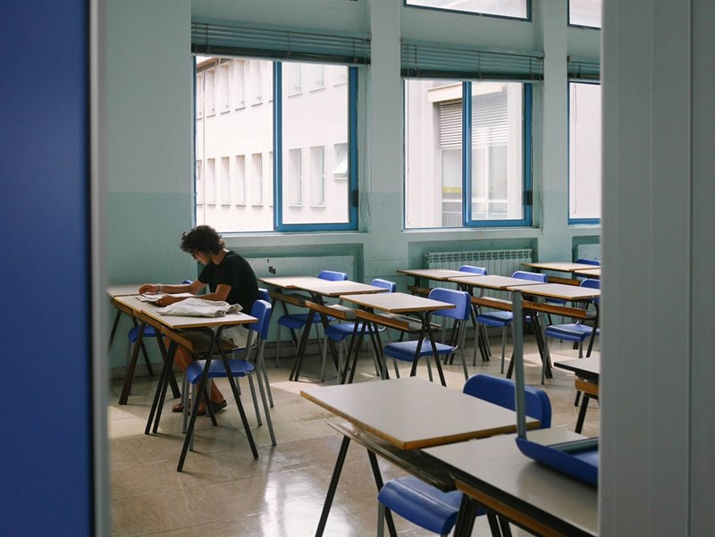 A student sits alone in detention after failing to bring a pencil to class three times. 