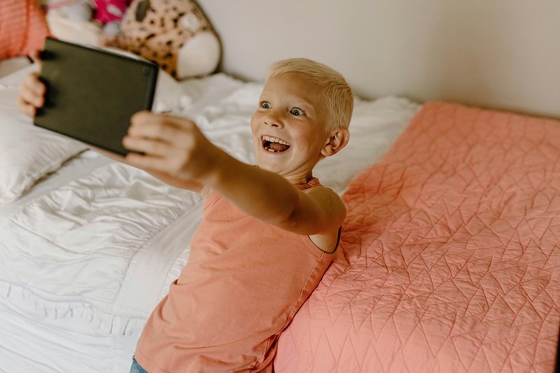 A little boy is playing with his tablet after getting home from a boring day at the park.