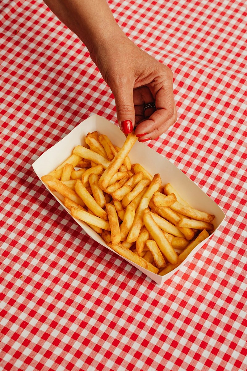 A basket of French fries on a restaurant table, illustrating the extra side order at the center of a couple’s disagreement.