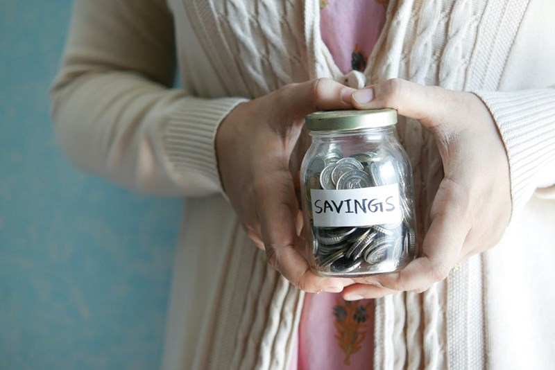 A savings jar representing college savings and long-term financial goals behind a young worker’s refusal to share her money.