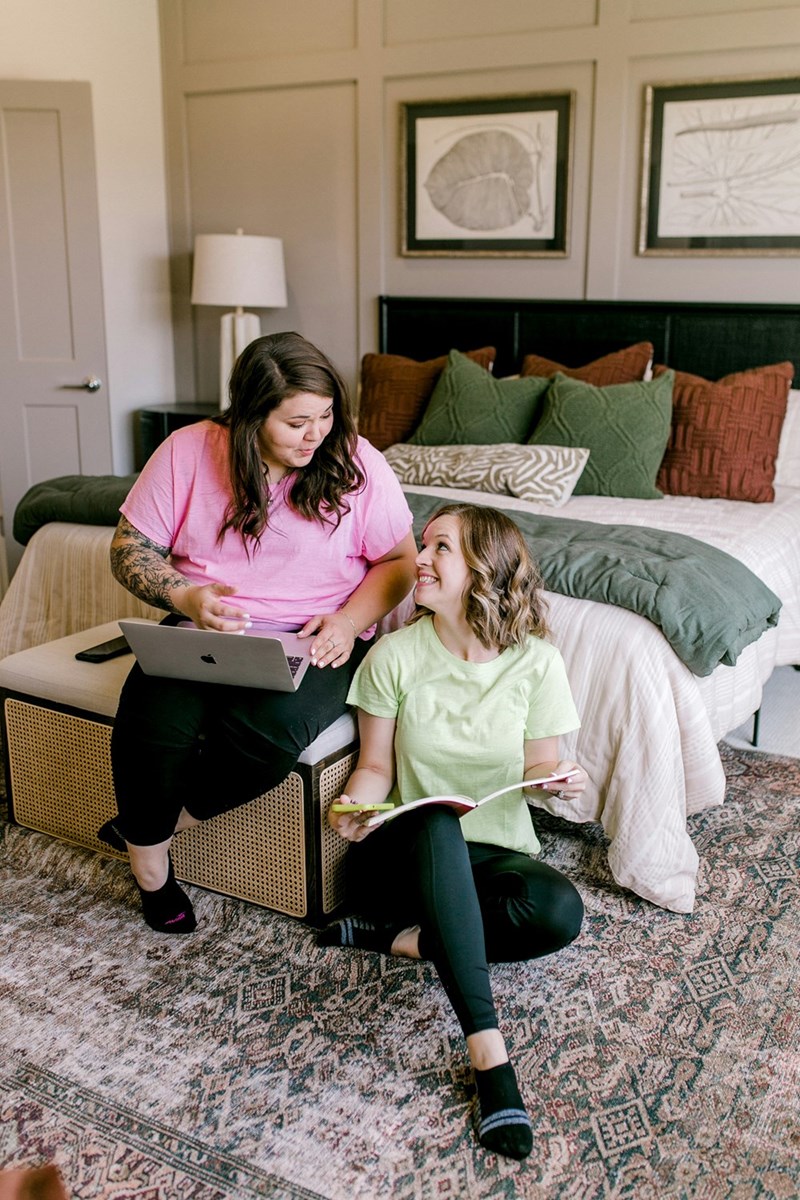 two woman laughing in a bedroom