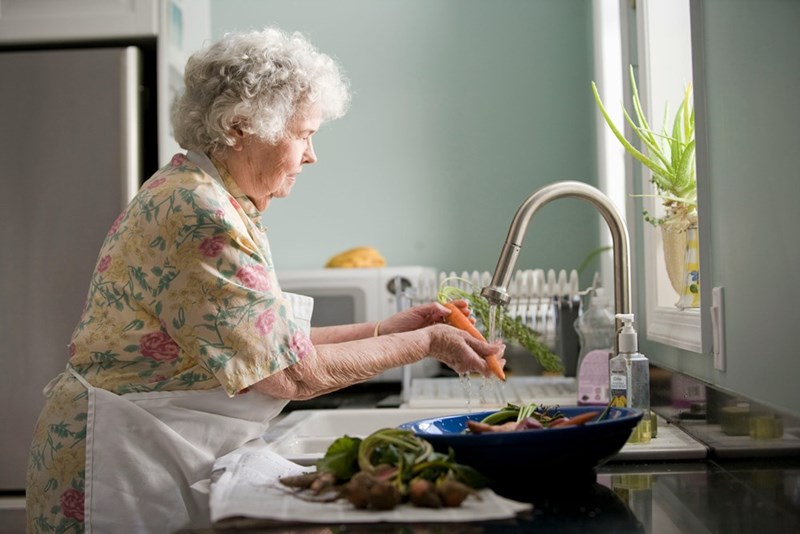 A grandmother preparing food in the kitchen, illustrating the work behind family meals at a grandparents’ house.