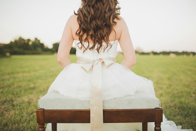 A bride sitting alone in her wedding dress, representing her standing firm on a wedding guest list despite family pressure.