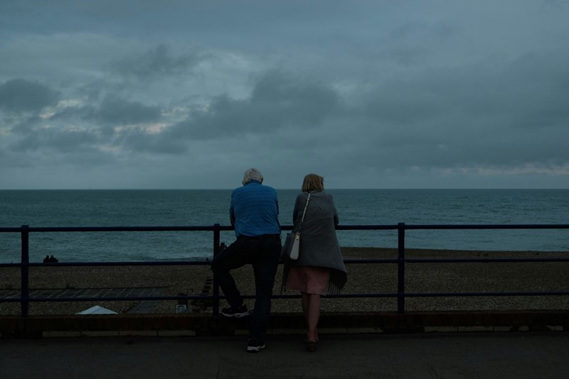 A couple watching the ocean from a distance, model image.