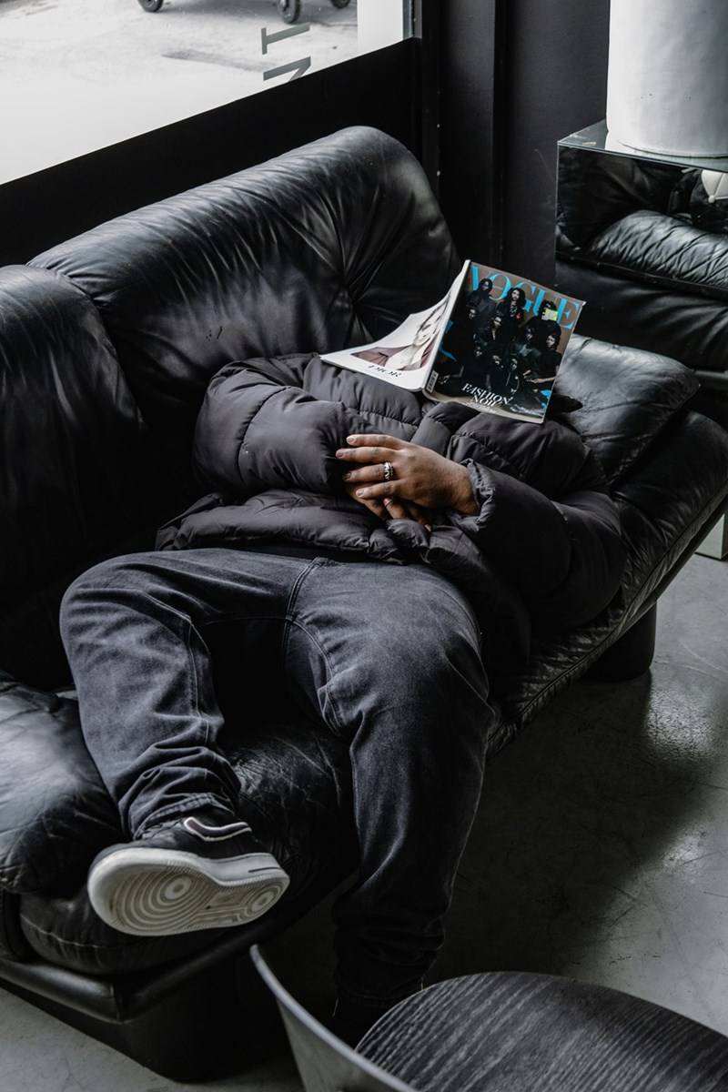 man laying on a couch with a magazine over his head