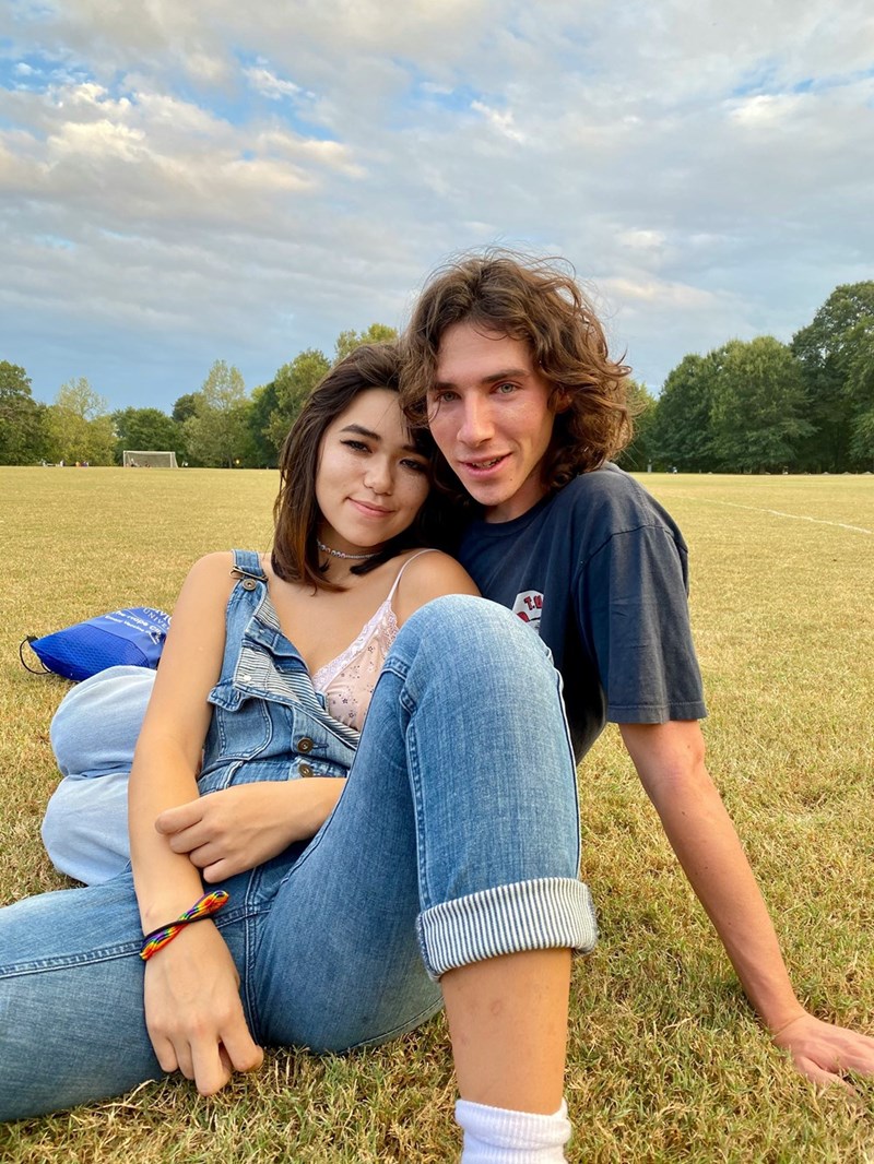 Young couple sitting together outdoors in a park, representing romantic relationships.