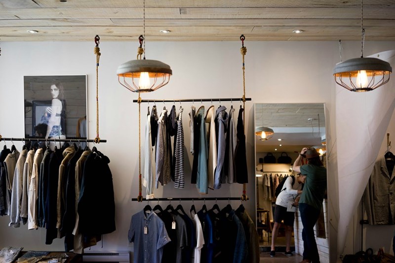 Clothing boutique interior with apparel displayed on hanging racks.