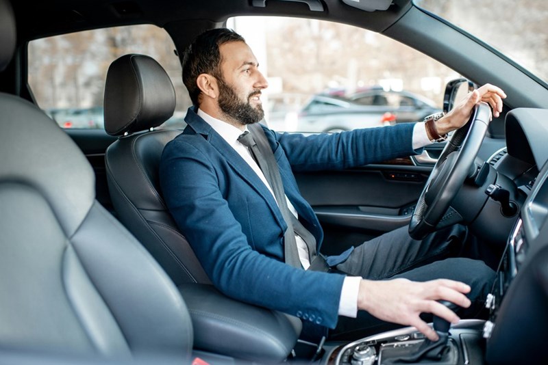 A commuter drives to work from the suburbs, while his CEO, who lives in the city, sits at home and works from his bed.