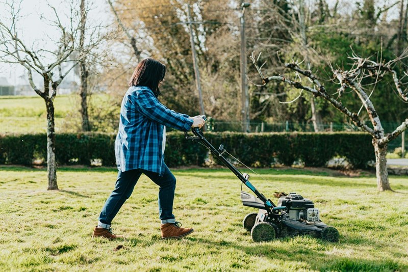 A woman mowing her neighbor's lawn.