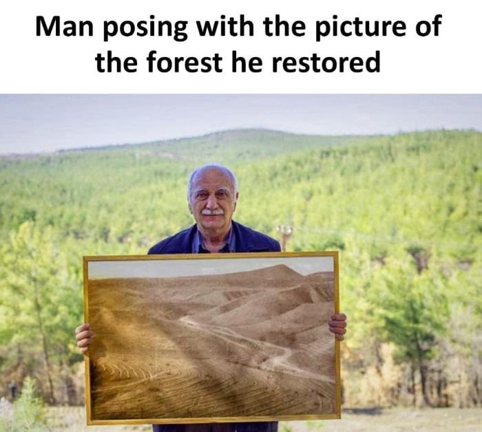 Man posing with the picture of the forest he restored