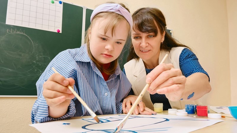 A special education teacher, who has different expectations for her students than an English teacher who specializes in advanced students, works with one of her special education students. 