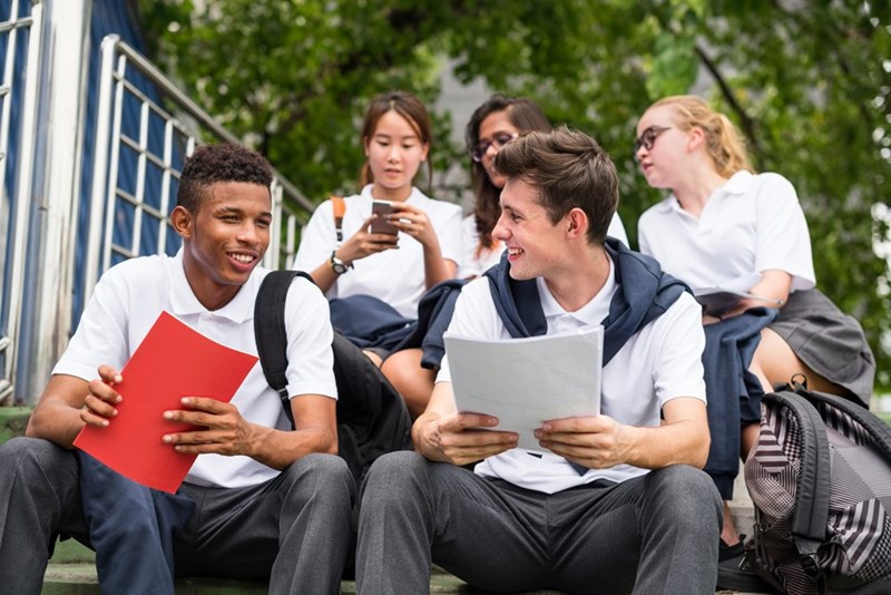 A group of students at an affluent private high school discusses their coursework between classes. 