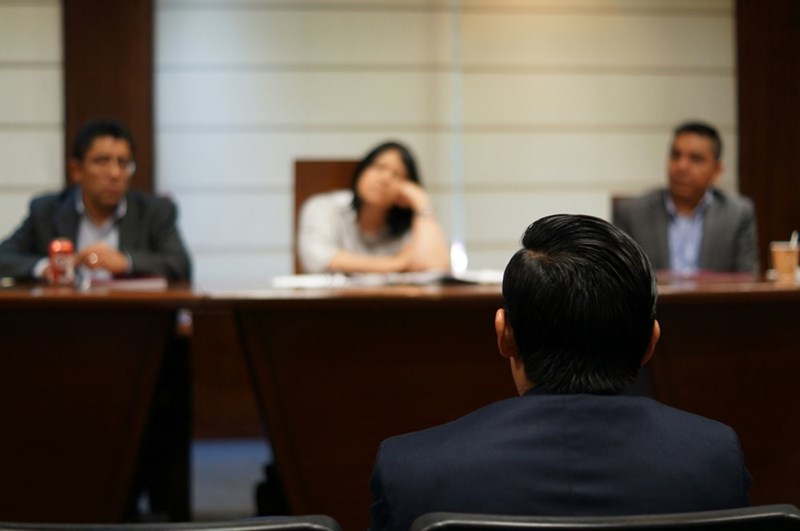 A man sitting in front of a trial in court, model image.