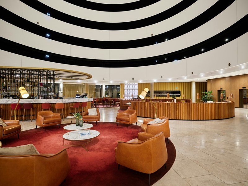 Hotel lobby with circular sofas and a bar zone, model image.