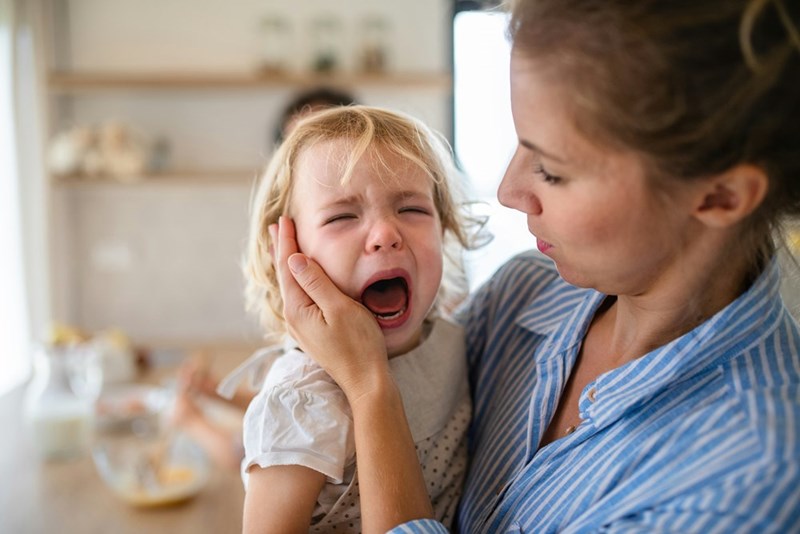 The toddler cries and screams to communicate her needs because she can't speak.
