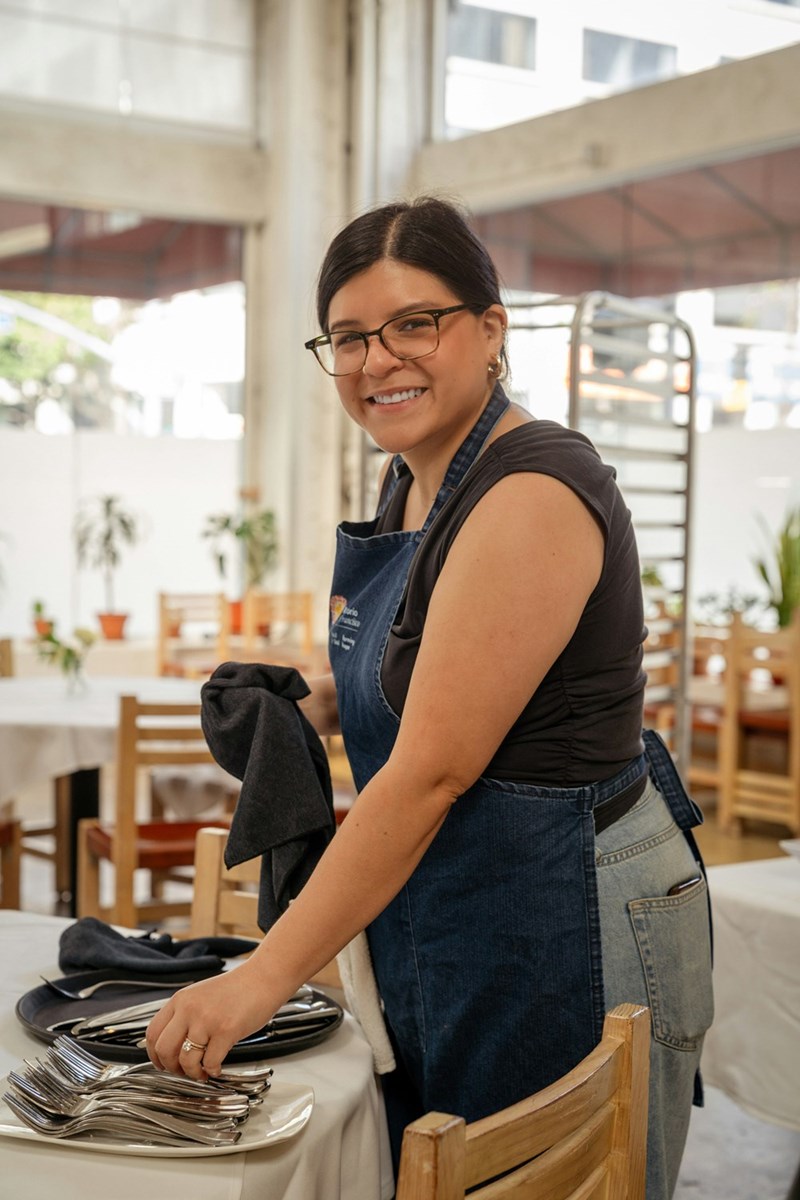 a woman in an apron setting a table