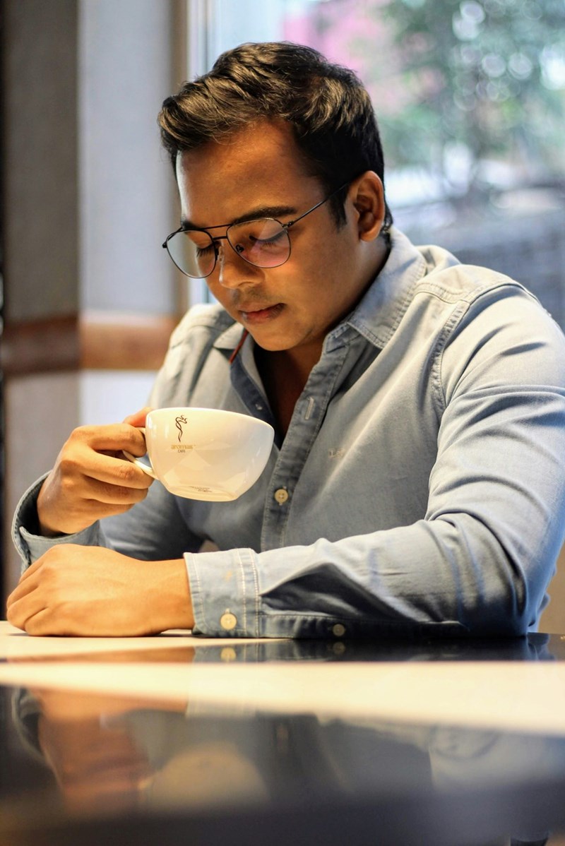 man drinking coffee and looking down sitting at a table