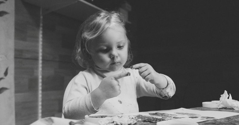 A little girl paints with finger paints