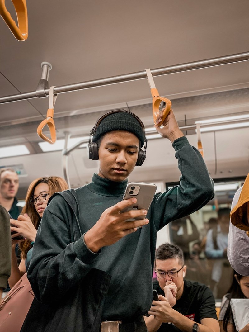 Model image of a man in a train holding a cellphone in his hand.