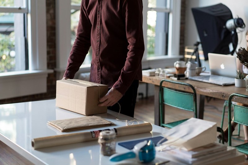 person holding cardboard box on desk