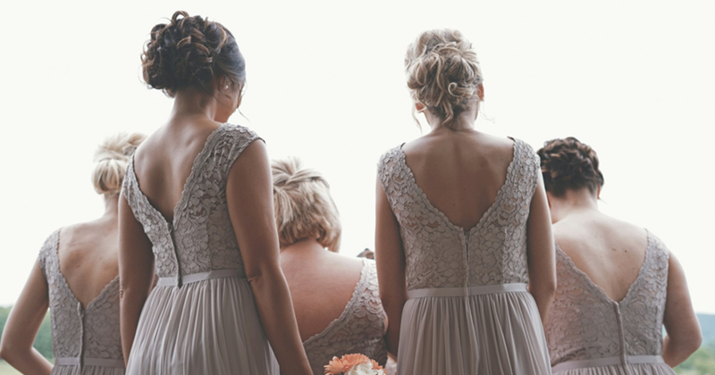 A representation of a group of bridesmaids pictured from the back, wearing grey dresses