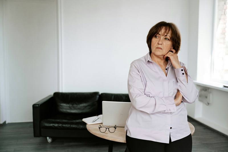 Middle-aged mom standing in her living room, looking disappointed.