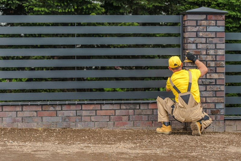 Contractor works on a residential fence project during a neighborhood property line improvement.