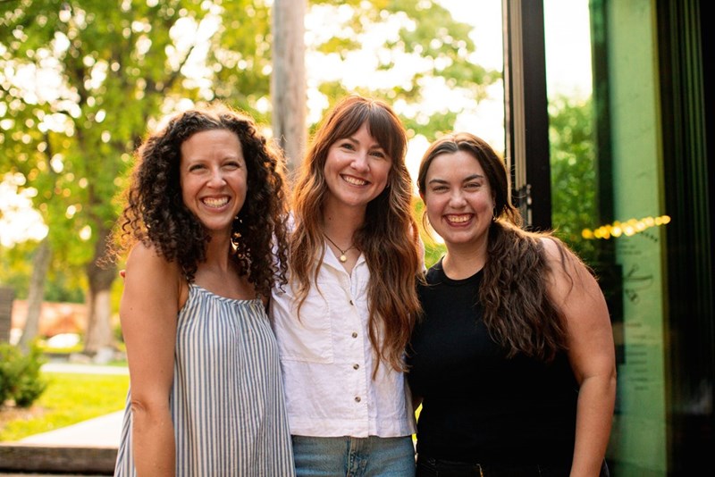 Three women smiling together outside, like business partners before a messy falling-out