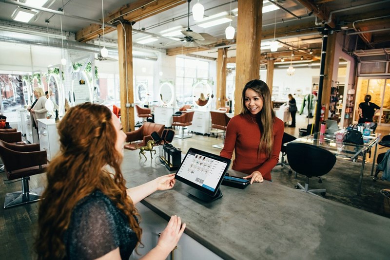 A customer and an employee talking at a front desk, model image.