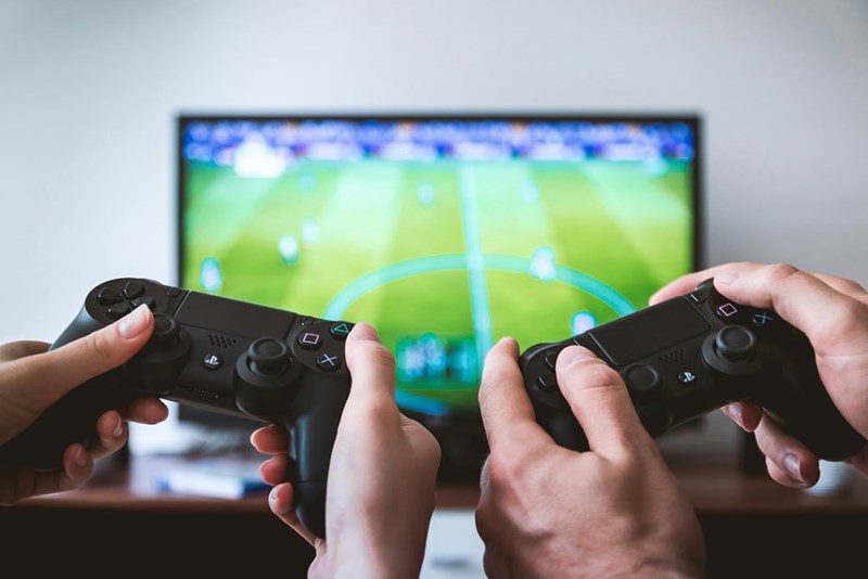 Two people holding PlayStation controllers in front of a television, picturing the gaming dispute that turned an ordinary dinner into a breakup.