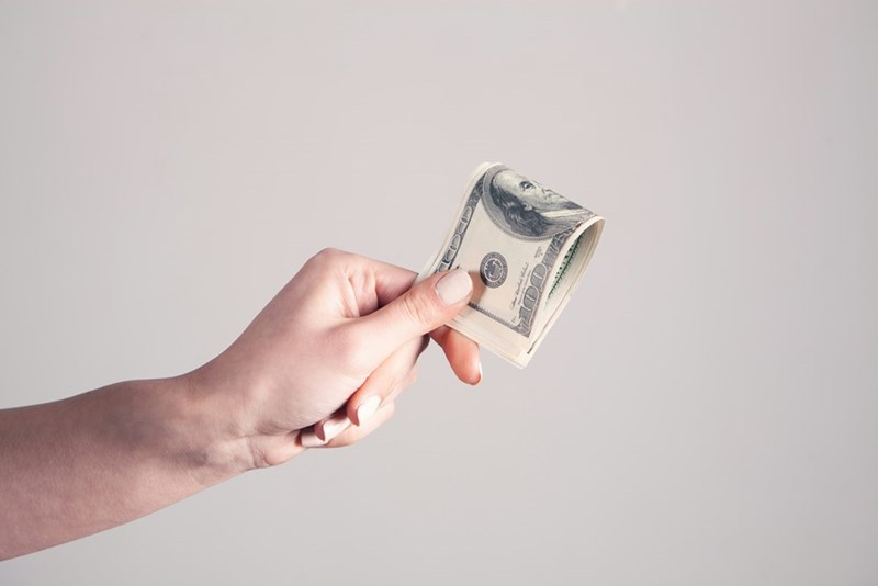Person holding cash while making a payment or deposit.